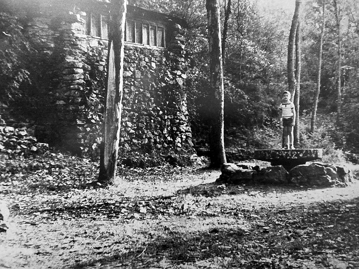 Fotografia antiga d'un nen sobre la font de pedra del jardí de la Coma de Sant Jaume
